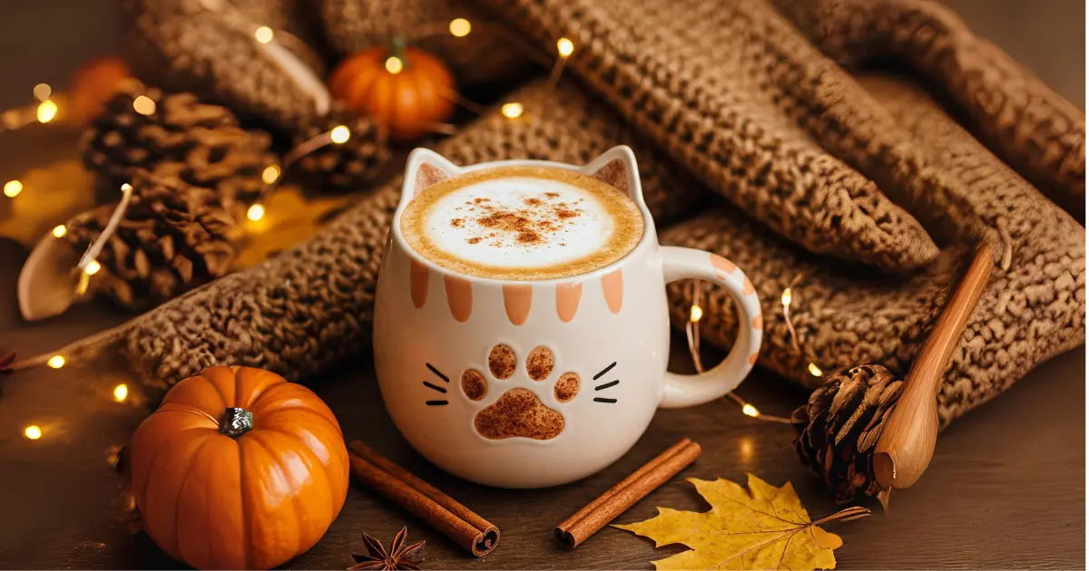 Fun and Creative Cat-Themed Drinks for Cat Lovers 3 A warm pumpkin spice latte in a cat-themed mug, topped with a cinnamon paw print, surrounded by pumpkins, autumn leaves, and a cozy knitted blanket.